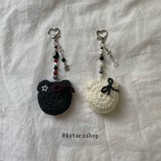 two crocheted keychains with charms attached to them on a white sheet