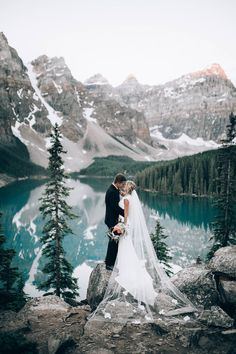 a couple standing next to each other on top of a mountain