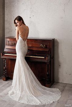 a woman in a wedding dress standing next to a piano and looking at the back of her gown