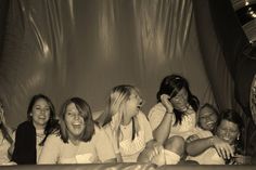 a group of women sitting next to each other in front of a curtained wall