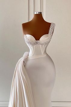 a white wedding dress on display in front of a mannequin headdress