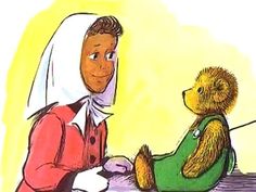 a woman sitting at a table with a teddy bear in front of her and another person standing next to her