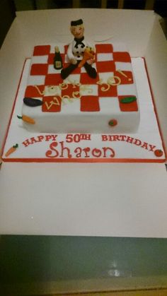 a birthday cake with a chef sitting on top of it in the shape of a checkered tablecloth