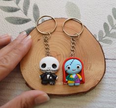 two key chains that have been placed on top of a piece of wood with a cartoon character