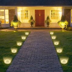 some lights that are on in the grass near a brick path leading to a house