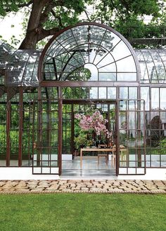 the inside of a glass house with flowers in it