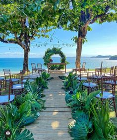 an outdoor ceremony set up with chairs and greenery on the ground, overlooking the ocean