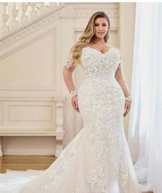 a woman in a white wedding dress standing next to a stair case with her hands on her hips