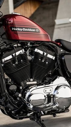 a red and black motorcycle parked in front of a building with the name harley davidson on it