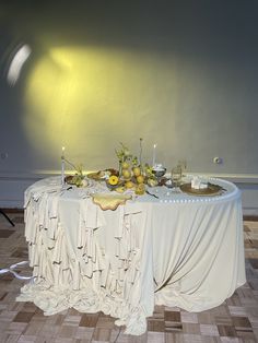 the table is set up with white linens and yellow flowers on it, along with candles