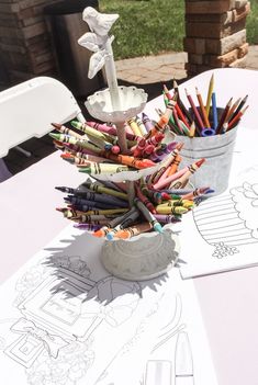 an arrangement of crayons in buckets on top of a table with paper cut outs