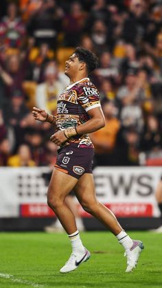 a rugby player is running on the field with his mouth open and hands in the air