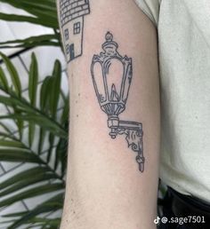 a man with a tattoo on his arm that has a house and lamp in it