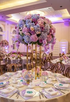 a tall vase filled with purple and blue flowers on top of a table covered in plates