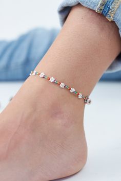 a woman's foot wearing a bracelet with flowers on the bottom and one beaded in