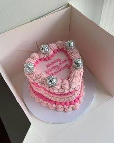 a heart shaped birthday cake in a pink box with silver decorations on the top and bottom