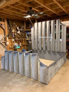 a large metal bed sitting inside of a garage next to a wall mounted ceiling fan