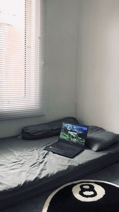 a laptop computer sitting on top of a bed in a room next to a window