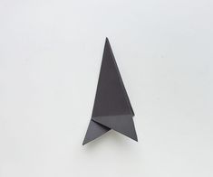 a black origami paper airplane on a white background with the bottom half folded up