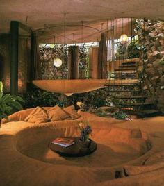 a living room filled with lots of furniture and plants next to a spiral stair case