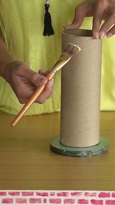 a person holding a paintbrush in front of a roll of toilet paper