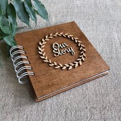 a wooden notebook with the word our story engraved on it next to a potted plant