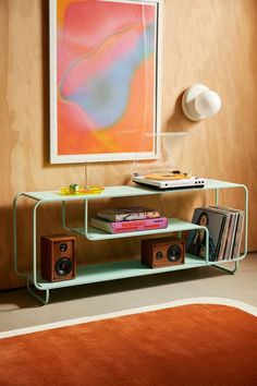 a living room with a shelf that has books on it and speakers in front of the wall