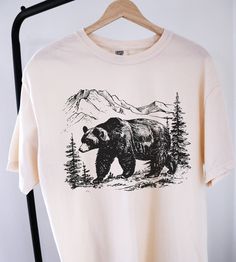 Vintage Bear Tshirt ⭐ Welcome to K & K Custom Tees! ⭐  - Indulge in pure comfort with our Comfort Colors Shirt. Soft, relaxed, and available in a variety of colors! ⭐SHIRT DETAILS⭐  -High Quality fabric  -100% ring-spun US cotton -Designed and printed in the USA  ⭐ PLEASE NOTE ⭐ -For an oversized look, we suggest to size up 1-2 sizes. These shirts run like standard unisex tees. Please see size chart for a more fitted look!  -Colors may vary based on your monitor or screen display! ⭐CARE INSTRUCT Bear Graphic Tee, Casual White T-shirt With Bear Print, Trendy Short Sleeve T-shirt With Bear Print, Affordable Casual T-shirt With Bear Design, Cheap Cotton T-shirt With Bear Print, Mountain Tshirt, Bear Design Graphic Tee Short Sleeve T-shirt, Nature Shirts, Bear Shirt