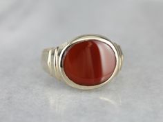 This beautiful mid century mounting combines late Art Nouveau and early Art Deco motifs. This beautifully styled ring could be for a man or a woman, and has a simple engraving on the sides and a warm rich Carnelian center. Carnelian is the reddish-orange version of Chalcedony, and can either be uniformly colored or have visible bands through the stone. This Carnelian is uniformly colored. Material: 14K Yellow Gold Gem: Carnelian Gem Measurements: 13.8 x 11.6 mm, Oval Size of Ring: 10.50 Marks: 1 Classic Ruby Ring With Polished Finish For Collectors, Mid-century Polished Formal Jewelry, Vintage Gemstone Signet Ring For Anniversary, Vintage Jewelry With Polished Finish Round Band, Vintage Jewelry With Polished Round Band, Collectible Heirloom Ruby Ring With Polished Finish, Modernist Oval Rings For Formal Events, Modernist Oval Rings For Formal Occasions, Mid-century Polished Finish Jewelry For Anniversary