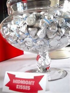 a glass bowl filled with lots of silver foiled chocolates on top of a table