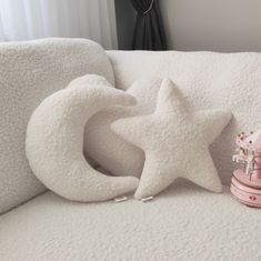 a white couch with a star shaped pillow on top of it next to a pink toy