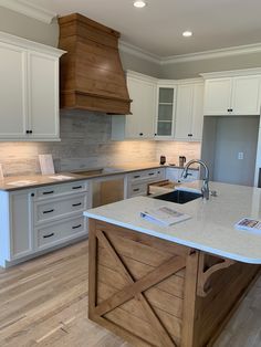 a large kitchen with white cabinets and wood accents on the counter tops, along with an island in the middle