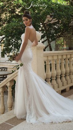 a woman in a wedding dress is standing on a balcony looking back at the camera