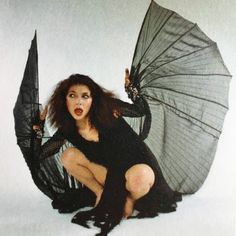 a woman kneeling down with an umbrella in her hand and holding it up to the side