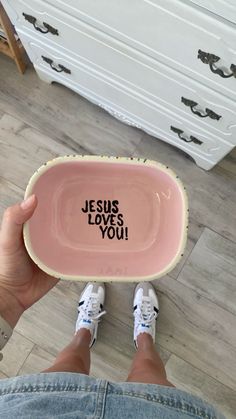 someone holding a pink bowl with jesus loves you written on it