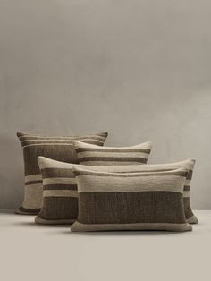 three pillows sitting next to each other in front of a gray wall and white floor