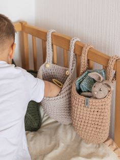 a little boy is playing with his crocheted bag and stuffed animals in it