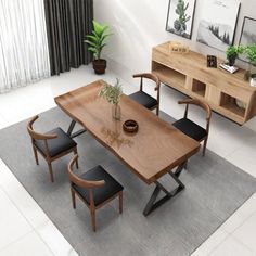 a dining table with four chairs and a potted plant on the side, in front of a window