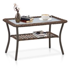 a wicker table with a book, coffee cup and glasses sitting on top of it