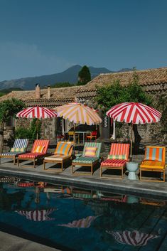 lounge chairs and umbrellas are lined up by the pool