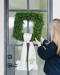 a woman placing a green wreath on the front door