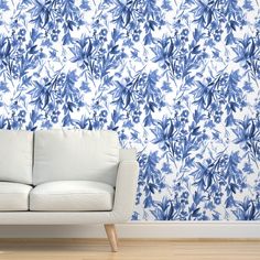 a white couch sitting in front of a blue and white floral wallpapered room