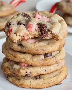 a stack of chocolate chip cookies with candy canes in the middle on a white plate