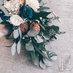 a bridal bouquet with flowers and greenery on the ground in front of someone's feet