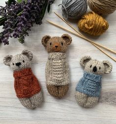 three knitted teddy bears sitting next to each other on top of a wooden table