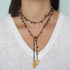 a woman wearing a long necklace with beads and charms on it's neckline