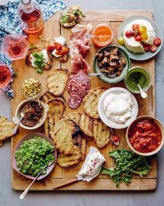 a wooden tray topped with different types of food and dips on top of it