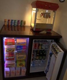 a small refrigerator with drinks and snacks in it next to a light that is on