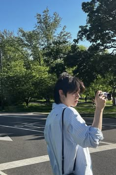 a woman standing in the middle of a street taking a photo with her cell phone