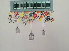 an electrical panel with bird cages hanging from it's sides and flowers painted on the wall